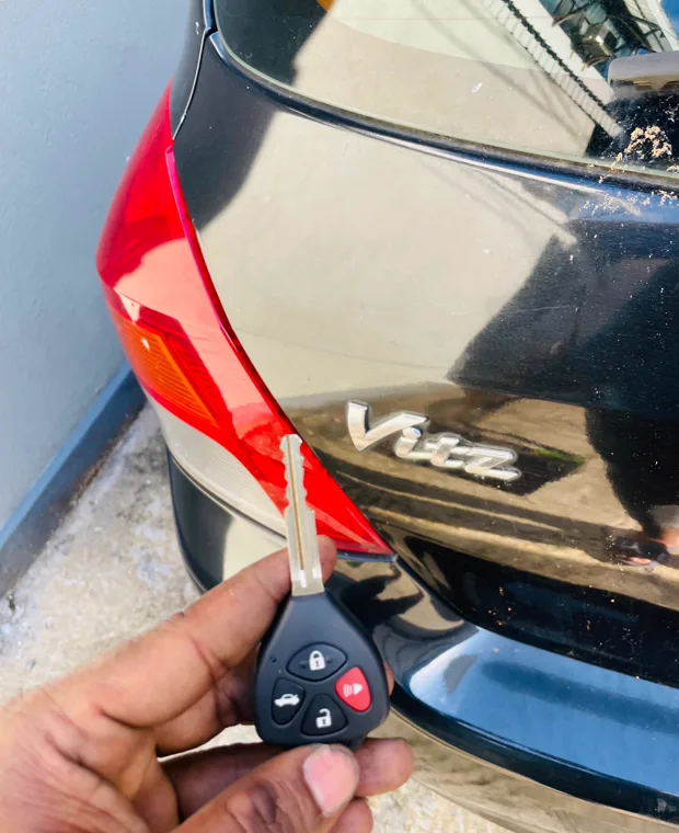 A newly programmed vehicle key beside a car