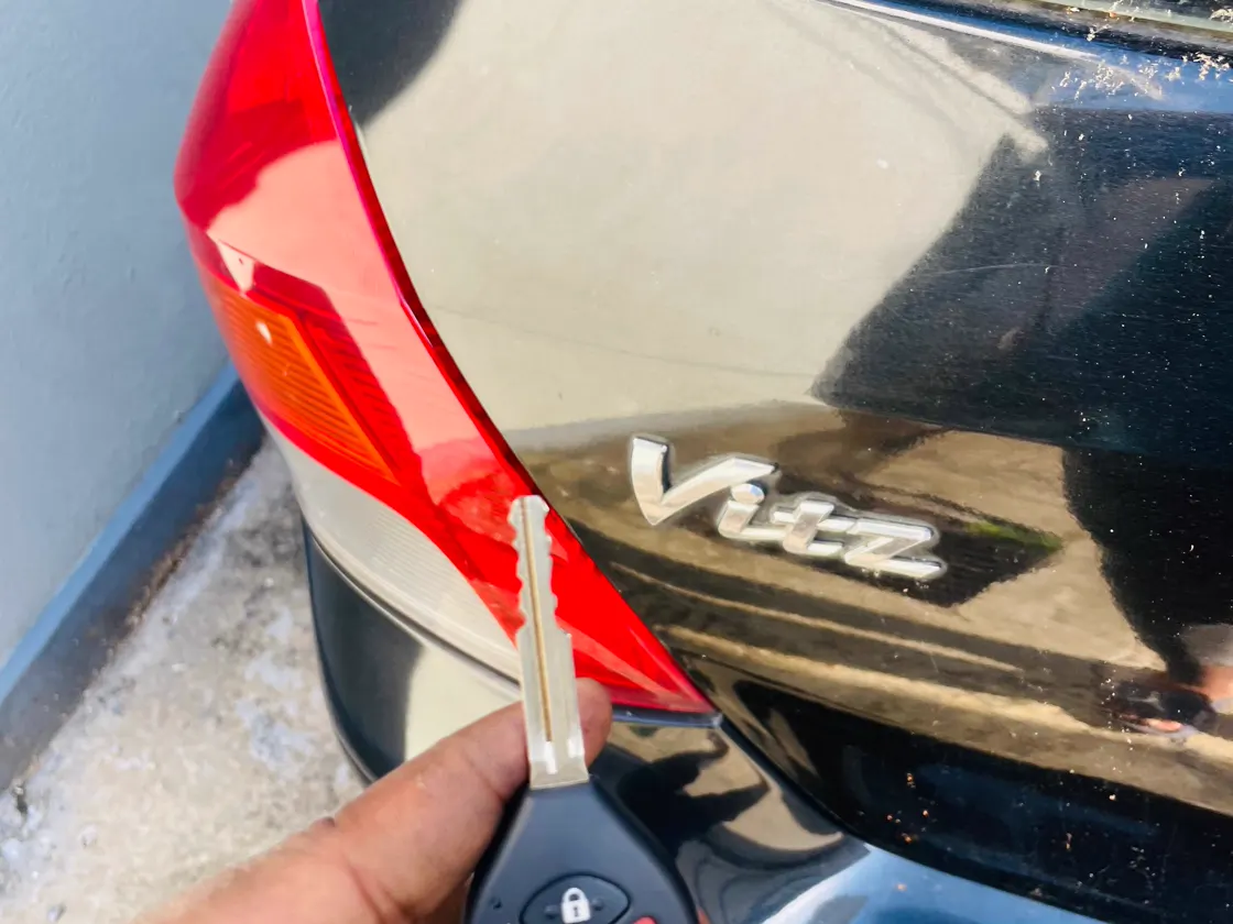 Key blade and remote beside a Toyota Vitz